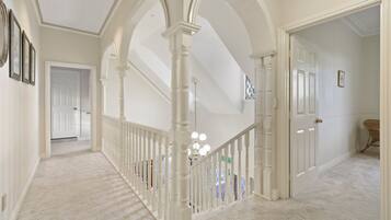 Un pasillo con columnas blancas, una escalera y una puerta que da a otra habitación.