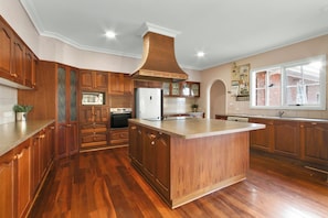 A spacious kitchen with wooden cabinetry, a central island, and a large window providing natural light.