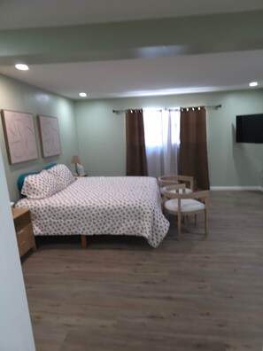 A bedroom with a bed, a chair, a TV, and artwork on the wall. - Your Home Away From Home- Private Oasis (Wichita)
