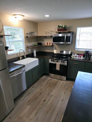 A modern kitchen with a stainless steel refrigerator, a built-in oven, a microwave, and a sink. - Your Home Away From Home- Private Oasis (Wichita)