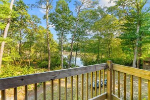 A wooden deck overlooking a forested area with a river. - Mashpee Retreat 3BR 2BA Pond Access & Water Views (Mashpee)
