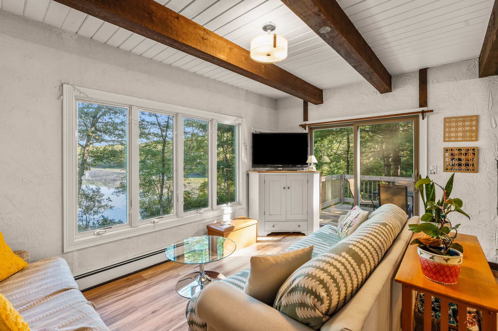 A spacious living room with large windows, a flat-screen TV, and a cozy seating area.