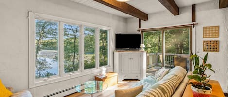 A spacious living room with large windows, a flat-screen TV, and a cozy seating area.