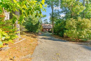 A gravel driveway leading to a house surrounded by dense trees and shrubs. - Mashpee Retreat 3BR 2BA Pond Access & Water Views (Mashpee)