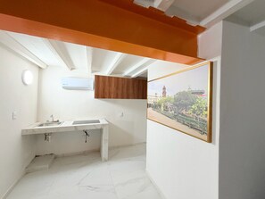 Ein kleines Badezimmer mit einem weißen Waschbecken, einem Holzschrank und einem gerahmten Bild an der Wand.