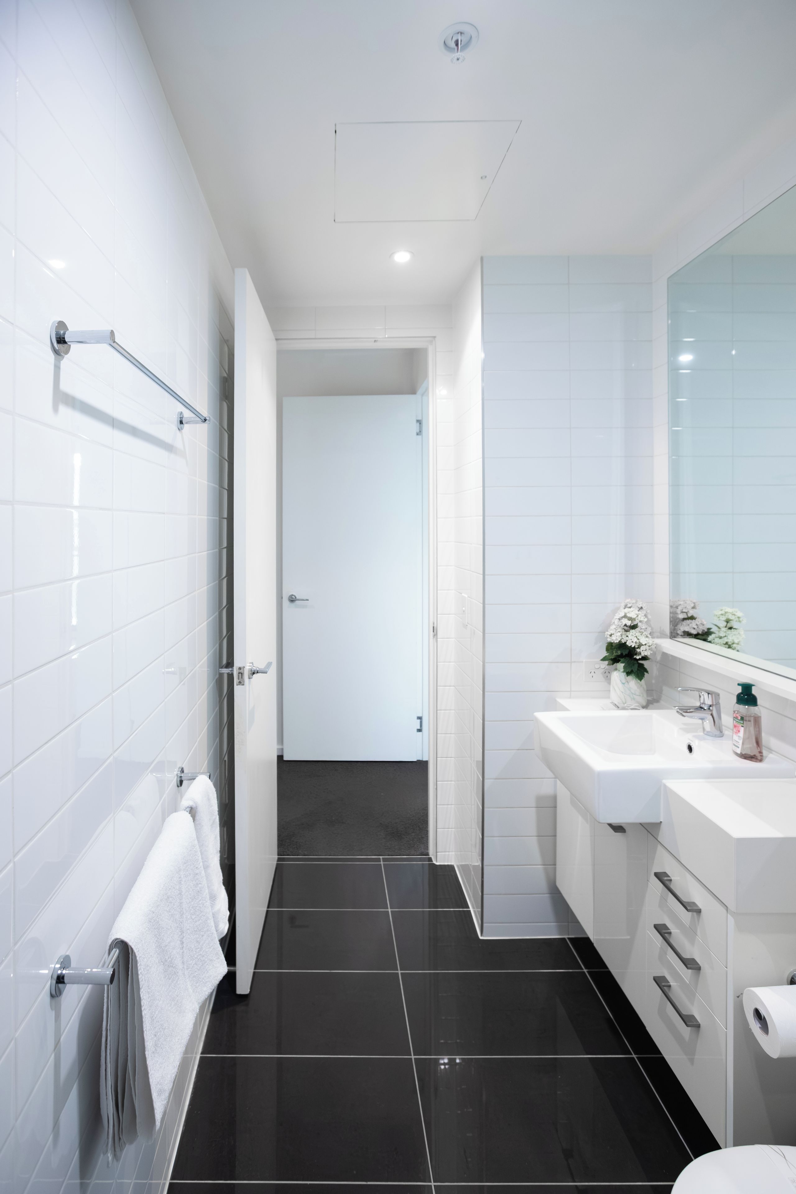 A modern bathroom with a walk-in shower, a large mirror, and a white sink.