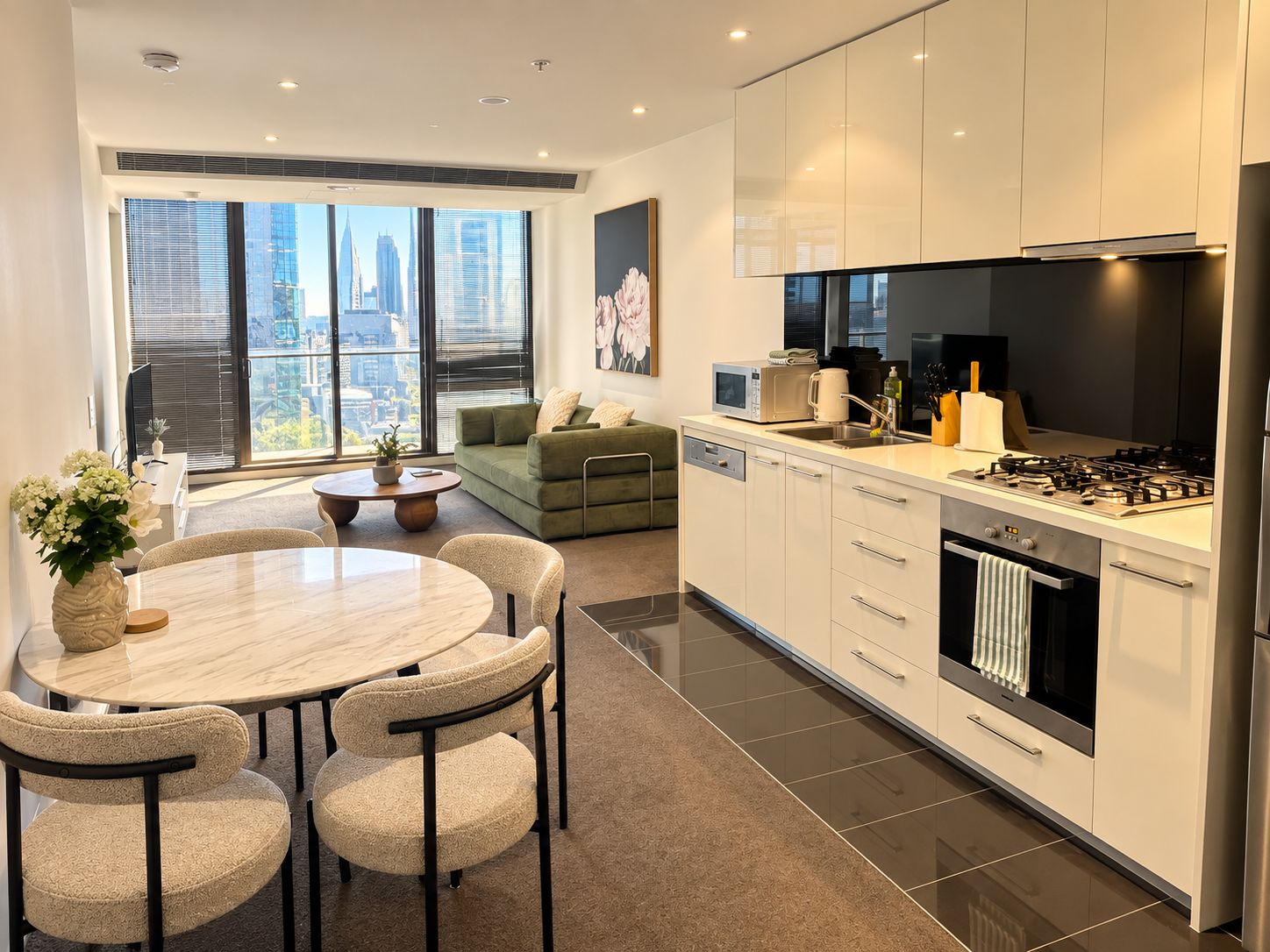 A modern kitchen with a dining area, large windows, and a city view.