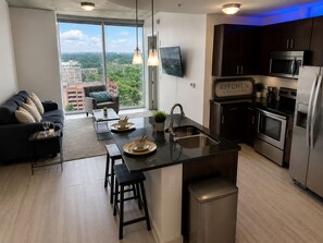 A modern kitchen with a central island, stainless steel appliances, and a view of the city through large windows.