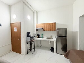 Eine kleine Küche mit Kühlschrank, Mikrowelle, Kaffeemaschine und Spüle.