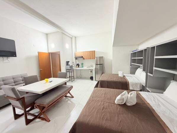 Quarto de hotel compacto com cozinha compacta, mesa de jantar, sofá e cama.