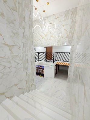 Eine Hotelhalle mit Marmorwänden, einer Treppe und einem Bereich mit Stockbetten.