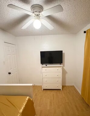 A bedroom with a bed, a white dresser, a television on top, a ceiling fan, and a door. - 3B/2Ba House 5 minutes from The Domain (Austin)