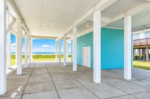 Shaded ground-level patio beneath the home with ocean views and room to gather after a day on the sand. - Beachfront | 5BR | Sleeps 18 | Gulf Decks (Galveston)