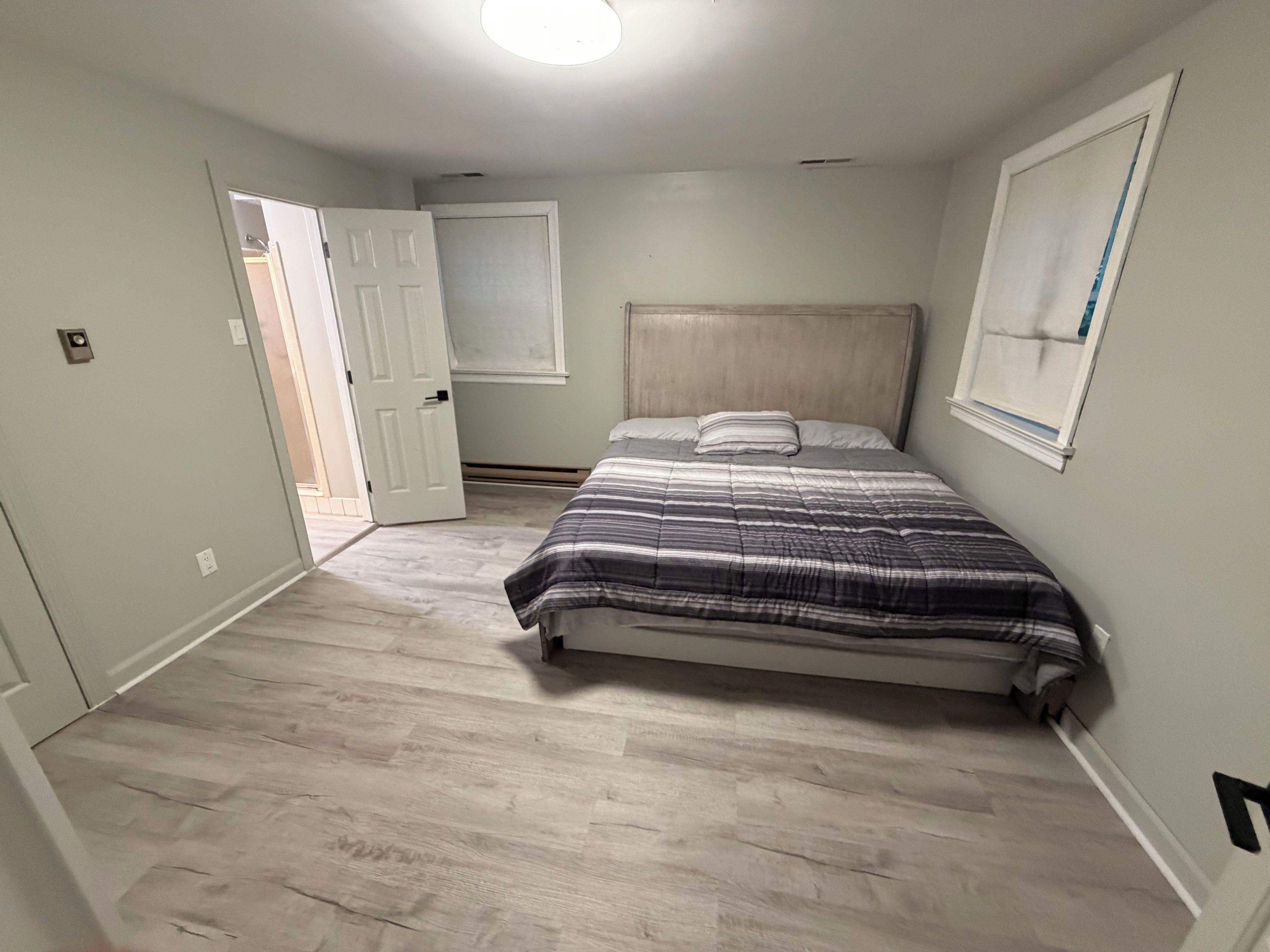 Ein Schlafzimmer mit Bett, Tür, Fenster und einer Lampe.