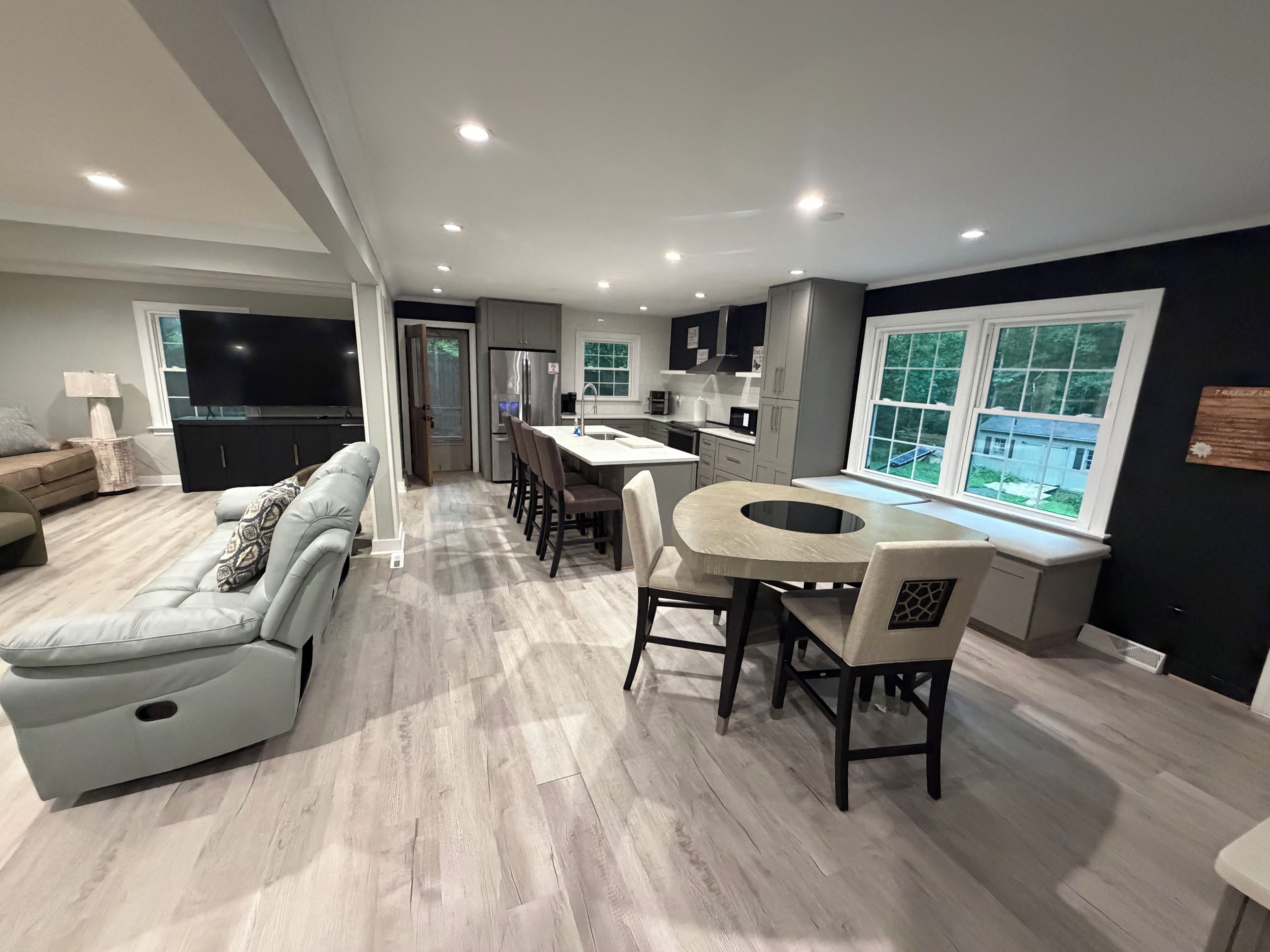 Una sala de estar moderna con un sofá, un comedor con una mesa redonda y una cocina con electrodomésticos integrados.