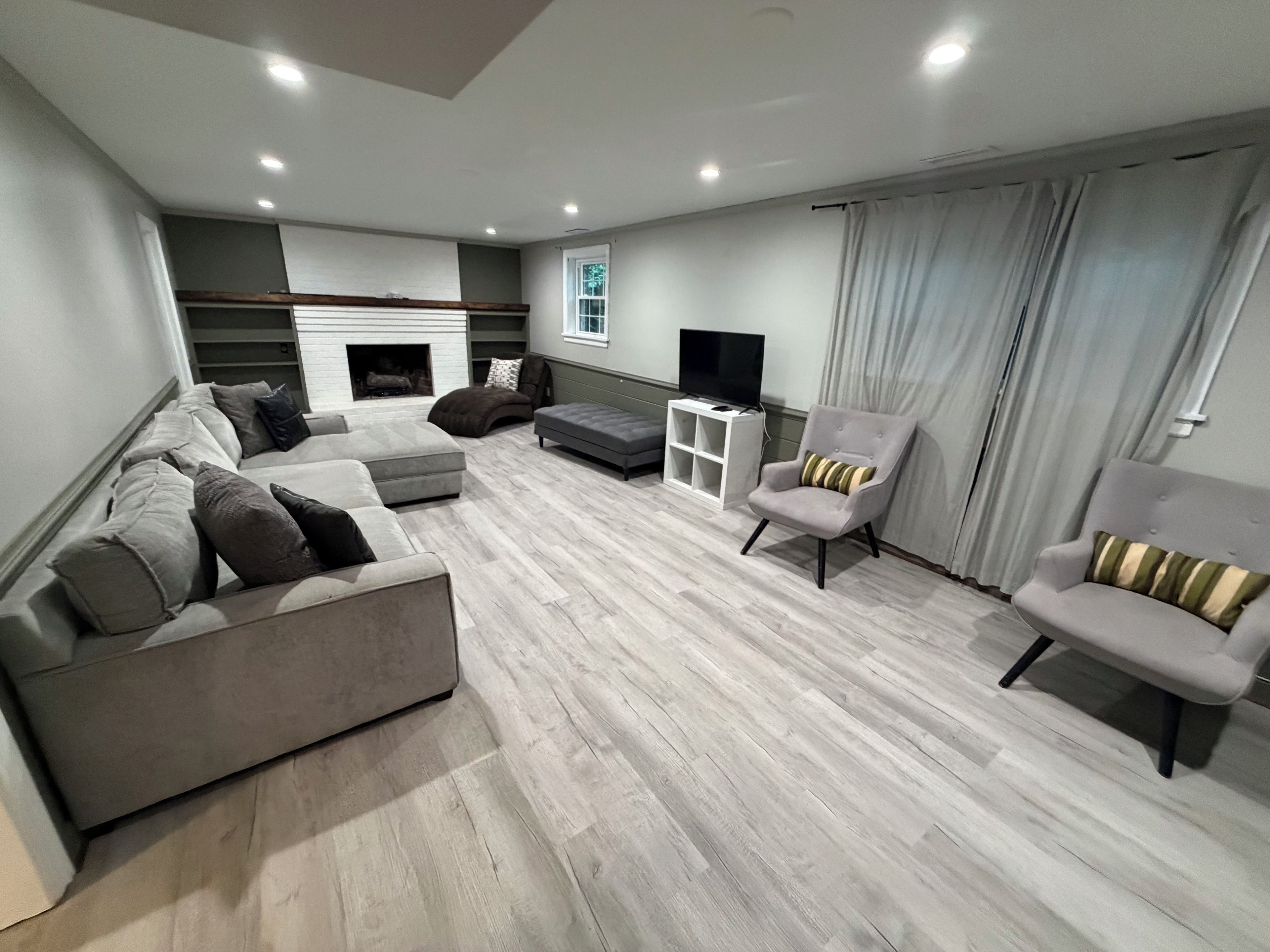 Un salon moderne avec une cheminée, des canapés, des fauteuils et un téléviseur.