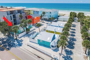 A coastal residential area with colorful houses, a beach, and a clear view of the ocean. - Aqua Tides Cottage #5|1br/1ba steps to beach (Indian Rocks Beach)