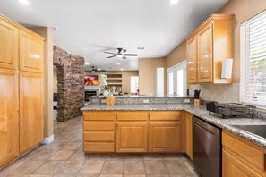 A kitchen with wooden cabinets, granite countertops, a built-in oven, and a stone accent wall. - Pool & Hot tub • Game Room • King Beds • 22 Guests Max (Las Vegas)