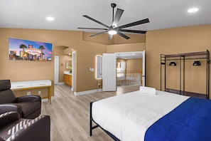 Een hotelkamer met een bed, een bureau, een stoel, een plafondventilator en een schilderij van Las Vegas.
