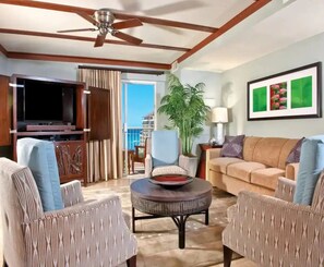 A living room with a ceiling fan, a TV, a sofa, a coffee table, and a potted plant. - Spacious 2-bedroom  condo with AC in beautiful Waikiki (Honolulu)
