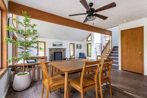A spacious dining area with a wooden table and chairs, a stone fireplace, and a staircase leading to another level. - Brown Bear Chalet Game Room Pool Table Fire Pit (Big Bass Lake)