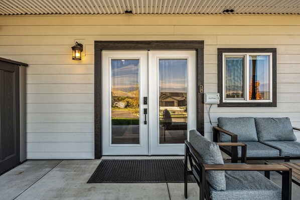 Une entrée de maison avec une porte double, un banc et une chaise à l’extérieur.