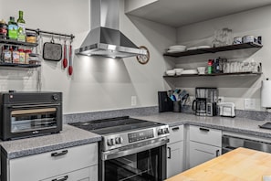 Une cuisine moderne équipée d’un four encastré, d’une plaque de cuisson et d’une machine à café posée sur le plan de travail.