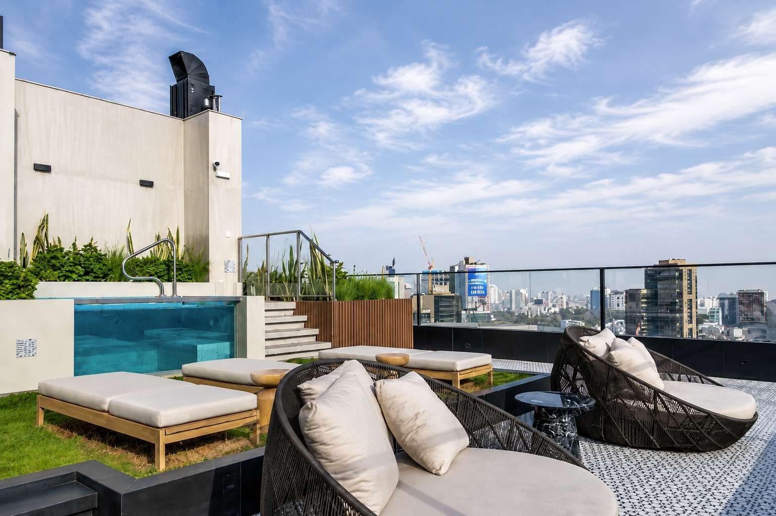Une terrasse sur le toit avec une piscine, des chaises longues et une vue sur la ville.