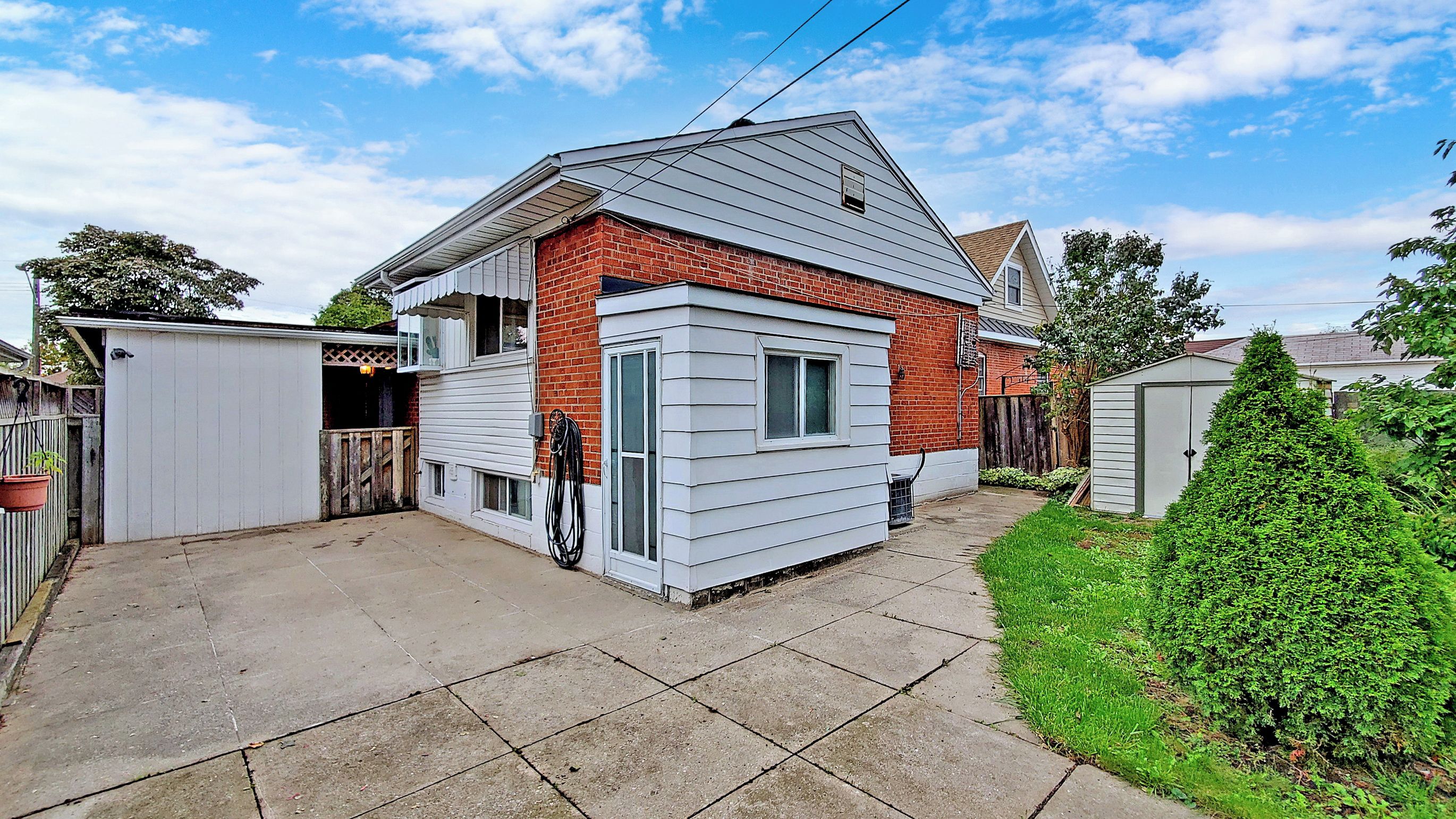 Une maison d’habitation avec une façade en briques et un garage recouvert de panneaux blancs.