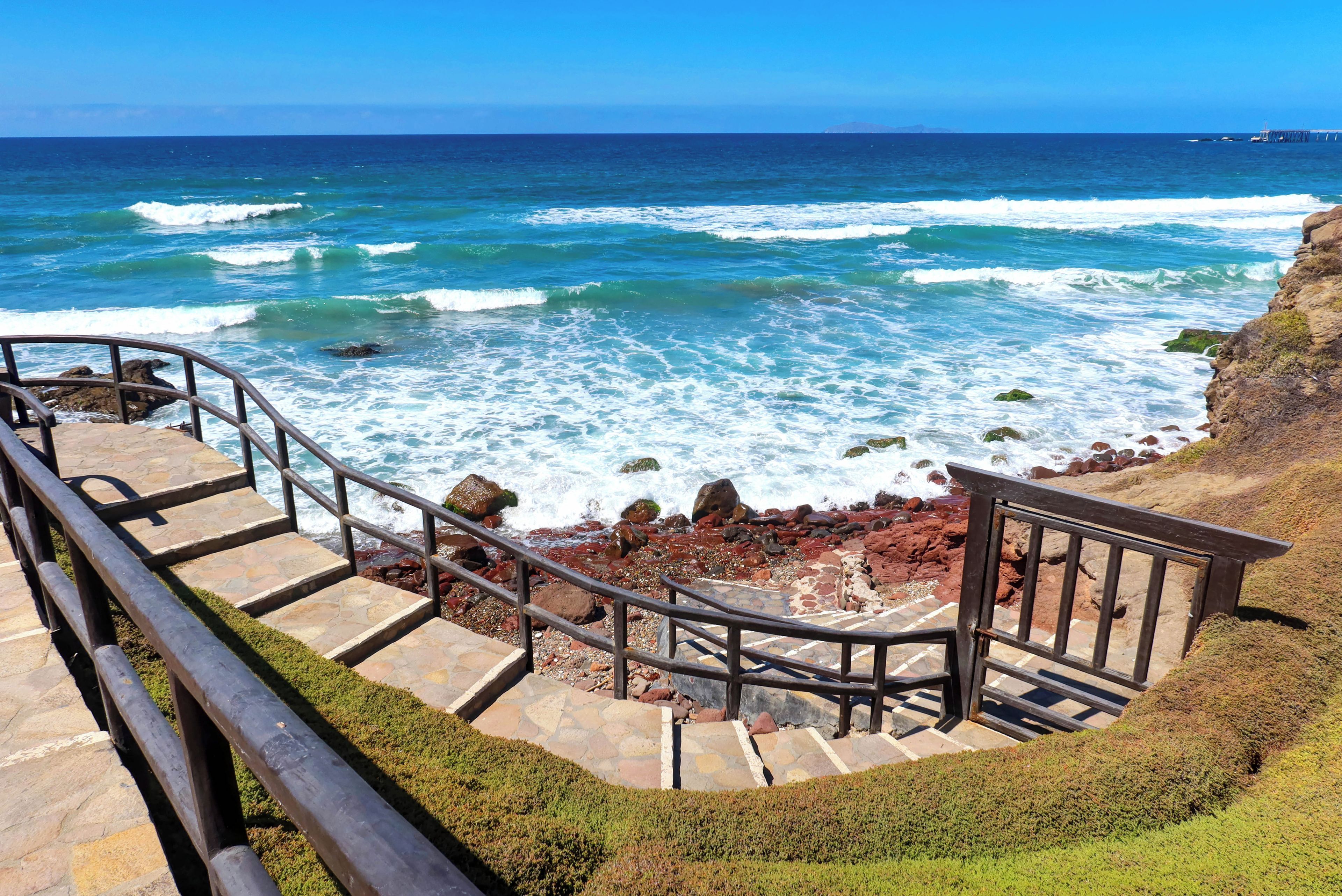 A staircase leading to a rocky beach with ocean waves.