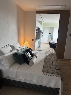 A hotel room with a bed, a desk, a chair, a water dispenser, and a television. - NEW BELLA VISTA (Puerto Vallarta)