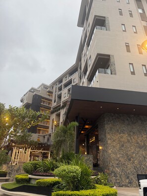 A multi-story hotel with a modern architectural design, featuring balconies, a stone facade, and a landscaped entrance area. - NEW BELLA VISTA (Puerto Vallarta)