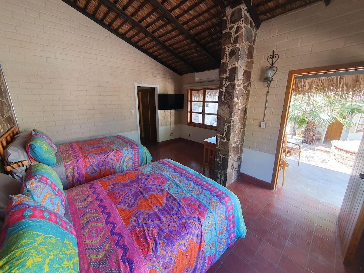Un dormitorio con cama, televisor, un pilar de piedra y una puerta que da a un espacio exterior.