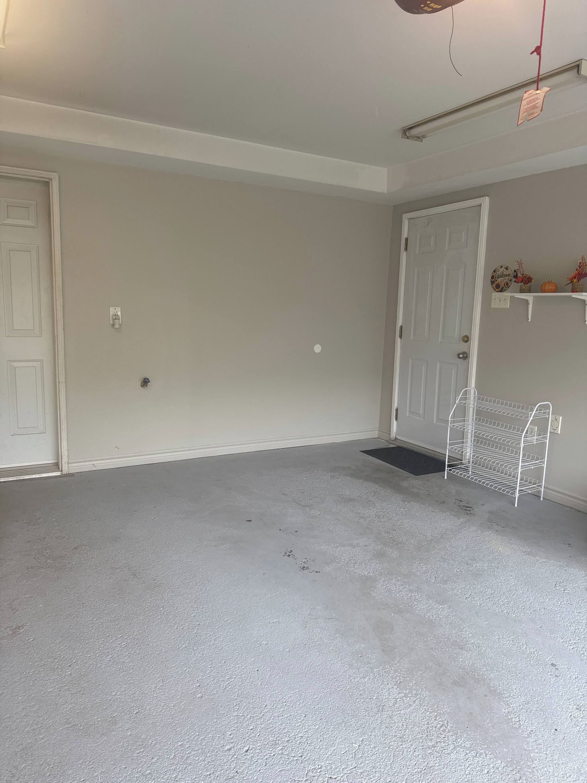 Una habitación con una puerta blanca, un estante blanco con adornos y una estantería metálica blanca.