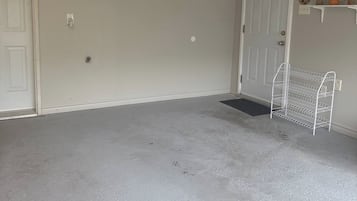 Una habitación con una puerta blanca, un estante blanco con adornos y una estantería metálica blanca.