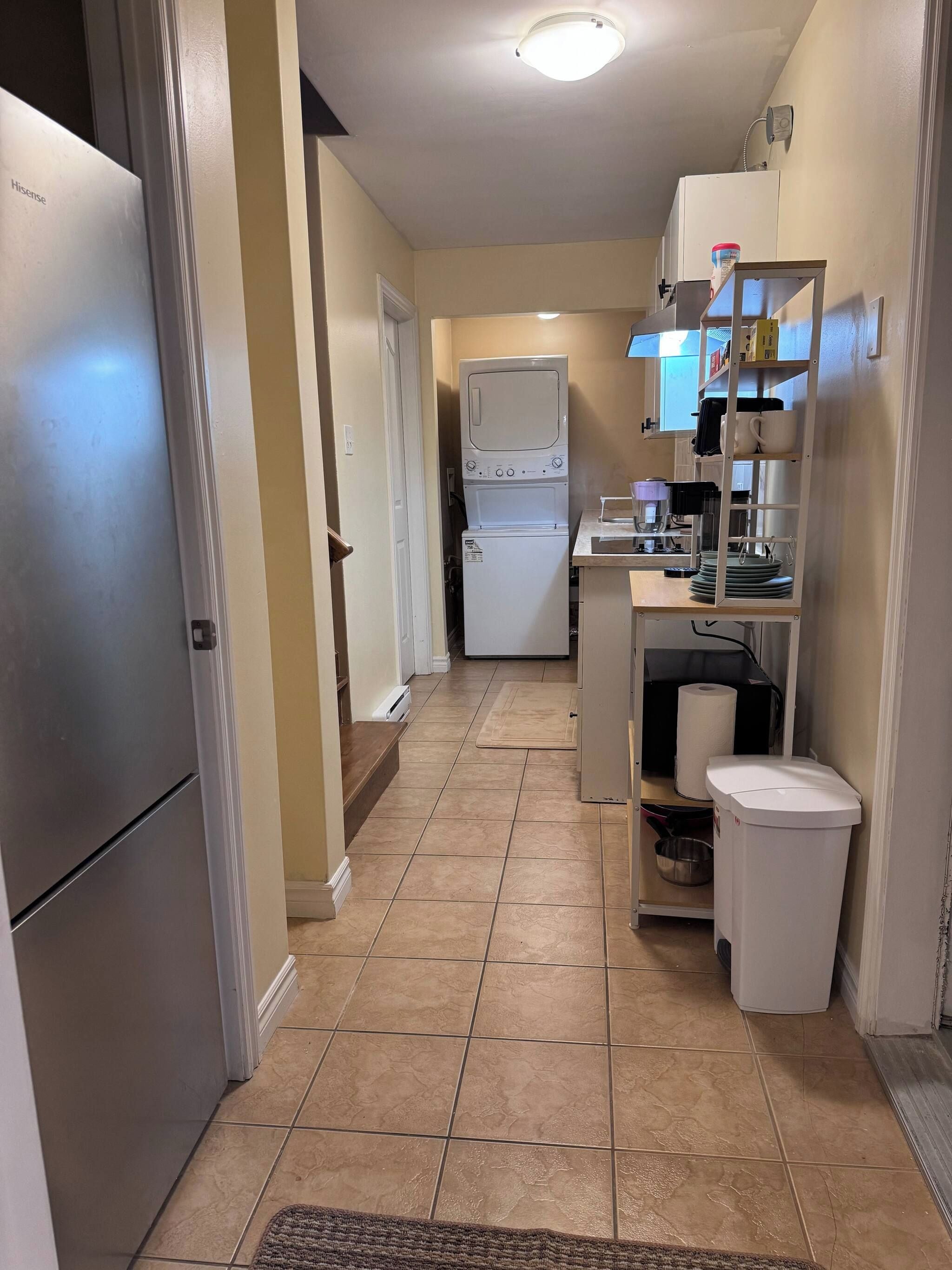 A compact kitchen with a refrigerator, washing machine, and a coffee maker on the counter.