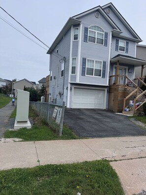 A two-story residential building with a garage, a wooden staircase, and a fenced yard. - Your Another Family Home (Beechville)