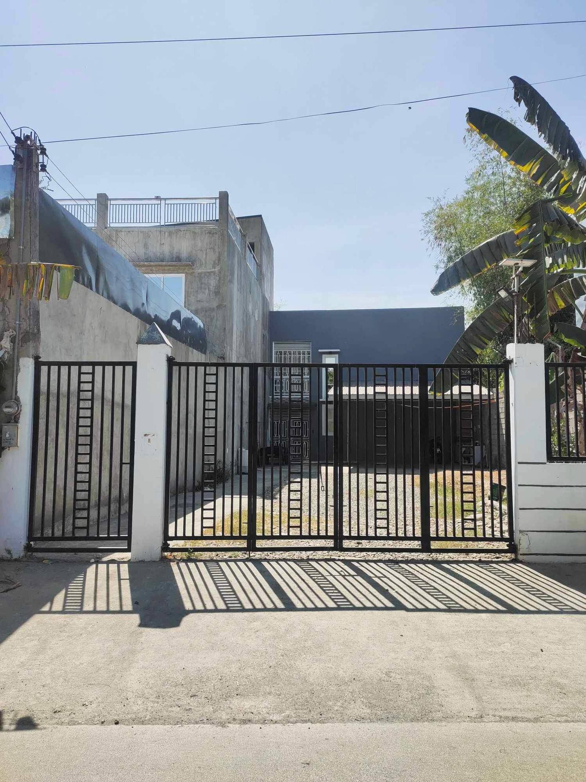 Propiedad amurallada con edificio de concreto, zona techada y acceso pavimentado.