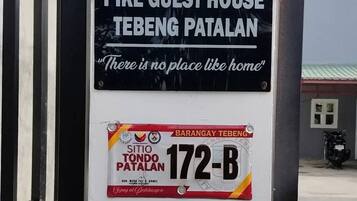A sign for Pike Guest House Tebeng Patalan with a slogan and a parking permit sticker.
