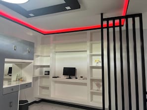 Un dormitorio moderno con televisor empotrado, estanterías y espejo.