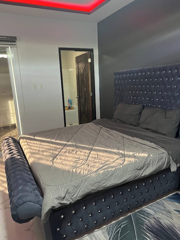 A bedroom with a large bed, a tufted headboard, and a modern design.