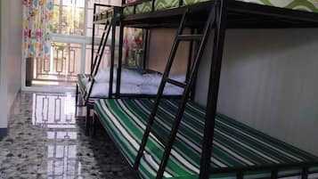 A dormitory room with bunk beds, a tiled floor, and a window with curtains.