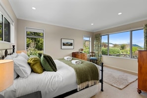A bedroom with a bed, a dresser, a nightstand, and a window with a view of greenery. - Loch View - Kinloch, Taupo *spa pool* (Kinloch)