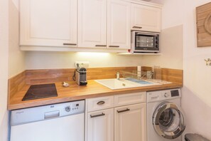 A compact kitchen with a microwave, a coffee maker, a dishwasher, and a washing machine. - Le Cosy des Montagnes - Welkeys (Megève)