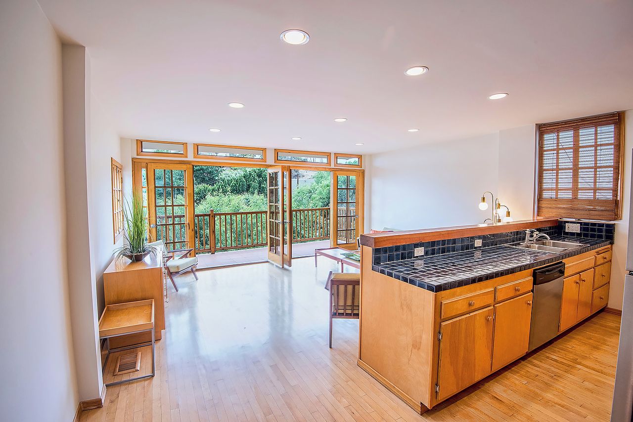 A spacious kitchen with wooden cabinets, a black countertop, and a built-in dishwasher.