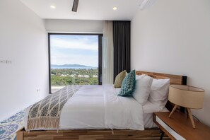 A bedroom with a large bed, a nightstand, a lamp, and a view of a landscape through a window. - Villa Satori 3 Bed Seaview Infinity Pool (Bophut, Koh Samui)