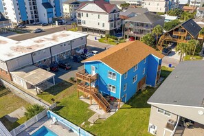 Edifício residencial com fachada azul, área externa coberta e piscina visível.