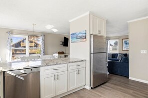 A modern kitchen with white cabinetry, a stainless steel refrigerator, and a Bosch dishwasher. - Family Tides: Unit 2 - Comfy 3BR Unit w/ Private Balcony (Walk to Beach) (North Myrtle Beach)