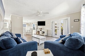 A living room with blue sofas, a white coffee table, and a ceiling fan. - Family Tides: Unit 2 - Comfy 3BR Unit w/ Private Balcony (Walk to Beach) (North Myrtle Beach)
