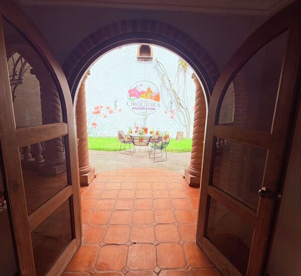 An entrance with a tiled patio leading to a dining area with a table and chairs.